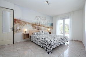 Relax in a spacious room with a large bed, patterned bedspread, and two bedside lamps.