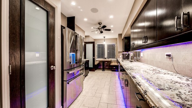 A modern kitchen with dark cabinetry, stainless steel appliances, and under-cabinet lighting.