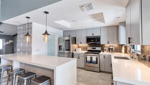 A modern kitchen with a large island, stainless steel appliances, and bar stools.