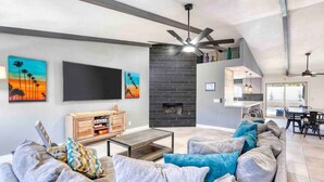 A modern living room with a fireplace, a TV, and a dining area.