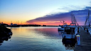 Een jachthaven met aangemeerde boten, kalm water en een zonsondergang.
