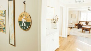 A living room with a white cabinet, a round wall clock, and a map. - NEW HotTub! Spacious cottage convenient to town, wineries & outdoor adventures! (Dahlonega)