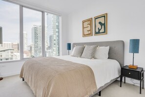 Contemporary bedroom with a large bed, two nightstands, and a city view.
