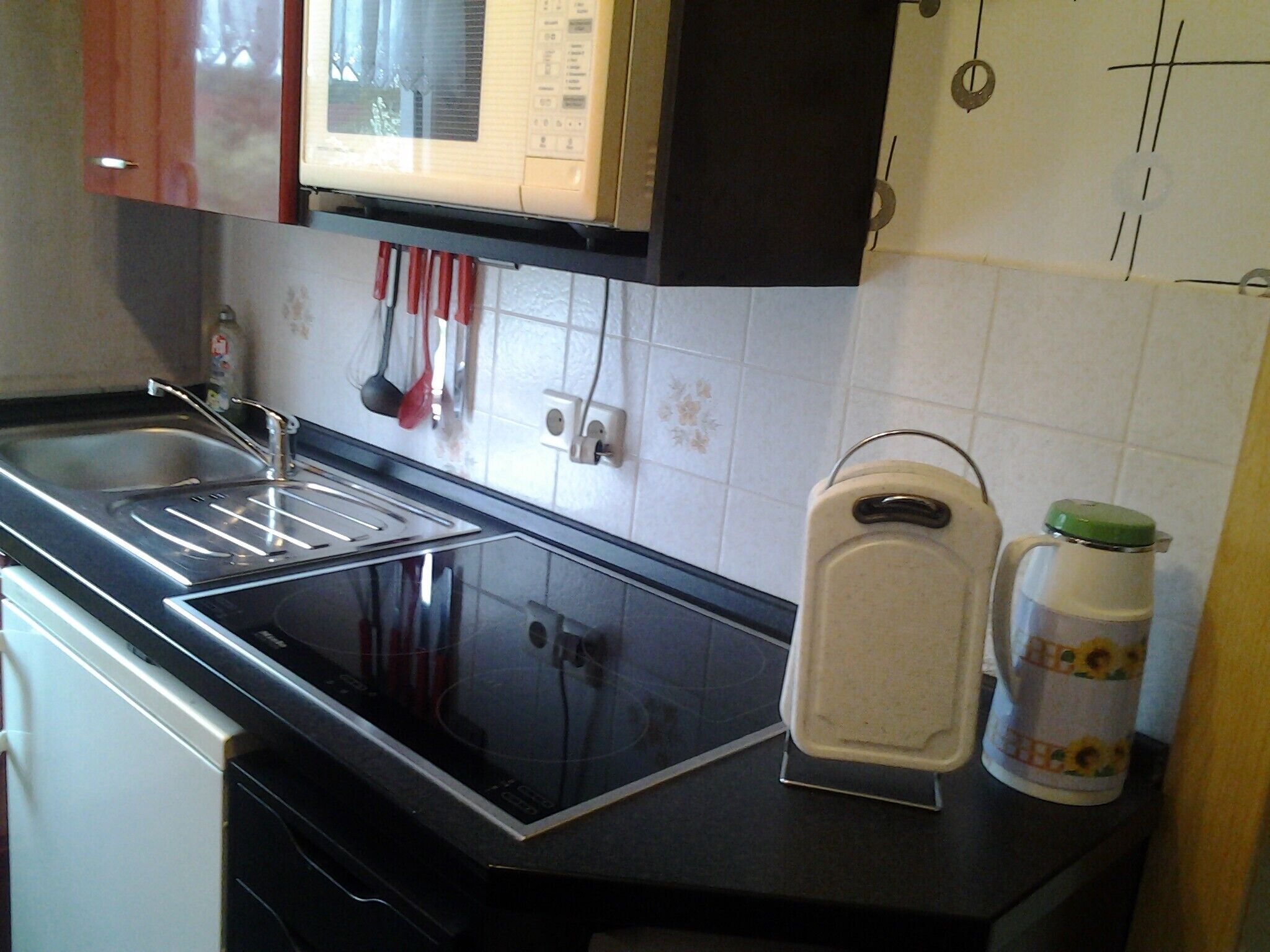 Uma cozinha com micro-ondas, pia e torradeira.