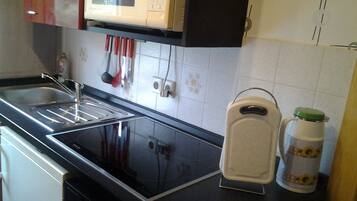 Uma cozinha com micro-ondas, pia e torradeira.