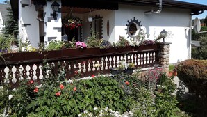 Un bâtiment blanc avec un toit noir, un balcon ornemental et un mur en pierre.