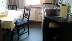 Une petite cuisine équipée d’une table et d’une chaise, d’une fenêtre et d’un radiateur.