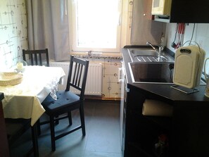 A compact kitchen with a table and chair, a window, and a radiator. - Holiday Home 'Werner' with Terrace & Wi-Fi (Neustadt)
