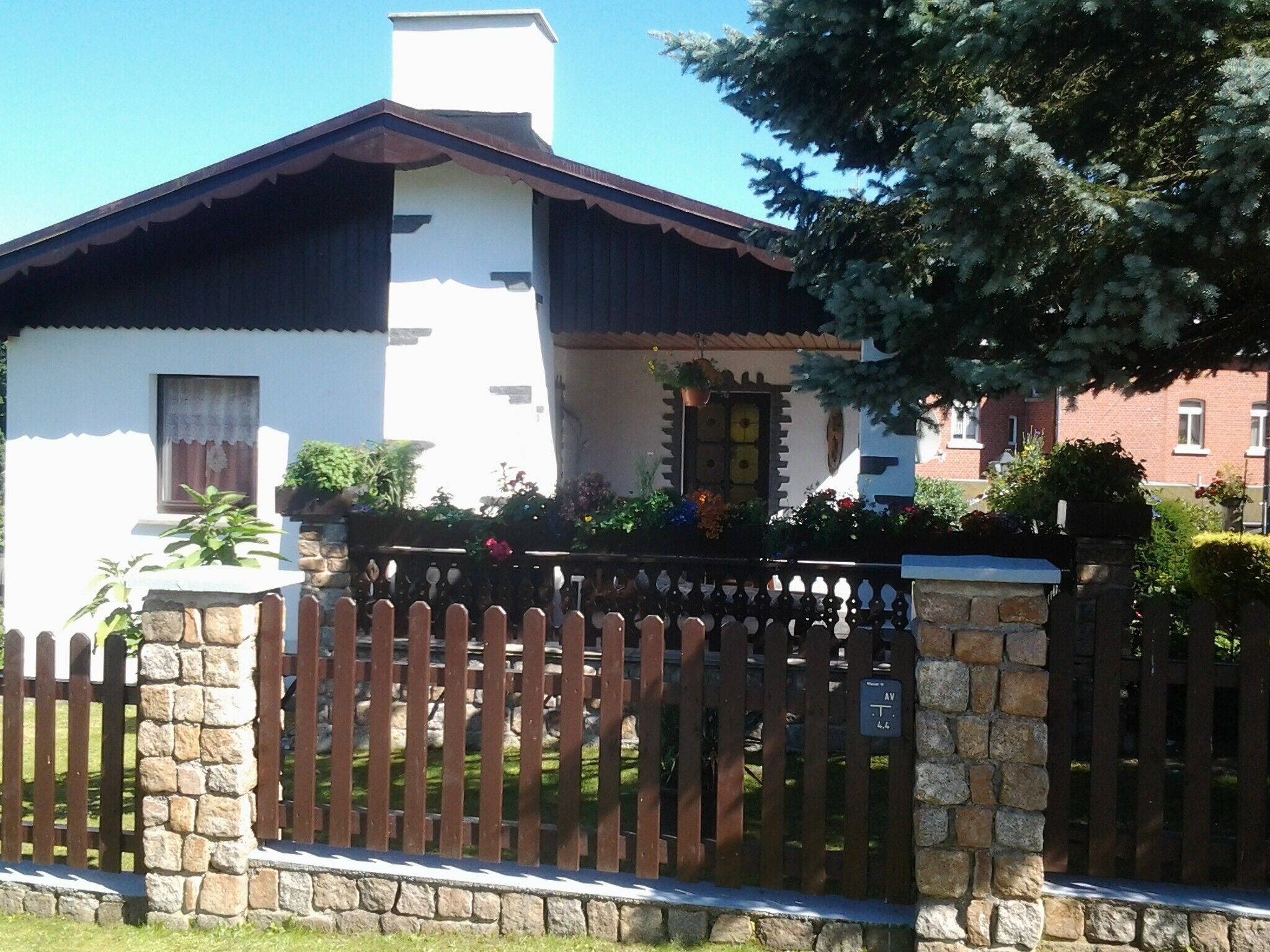 A traditional house with a stone fence, a wooden gate, and a small garden.