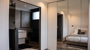 A modern bedroom with a large mirror, a bed with pillows, a nightstand, and a built-in wardrobe. - TERRASSE PROVENCE PAGNOL ***** (Aubagne)