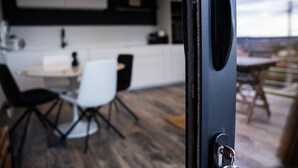 A modern kitchen with white cabinets, a dining area with a white table and chairs, and a view of the cityscape. - TERRASSE PROVENCE PAGNOL ***** (Aubagne)