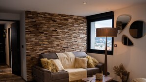 A modern living room with a brown leather sofa, patterned cushions, a woven rug, and a wooden wall. - TERRASSE PROVENCE PAGNOL ***** (Aubagne)