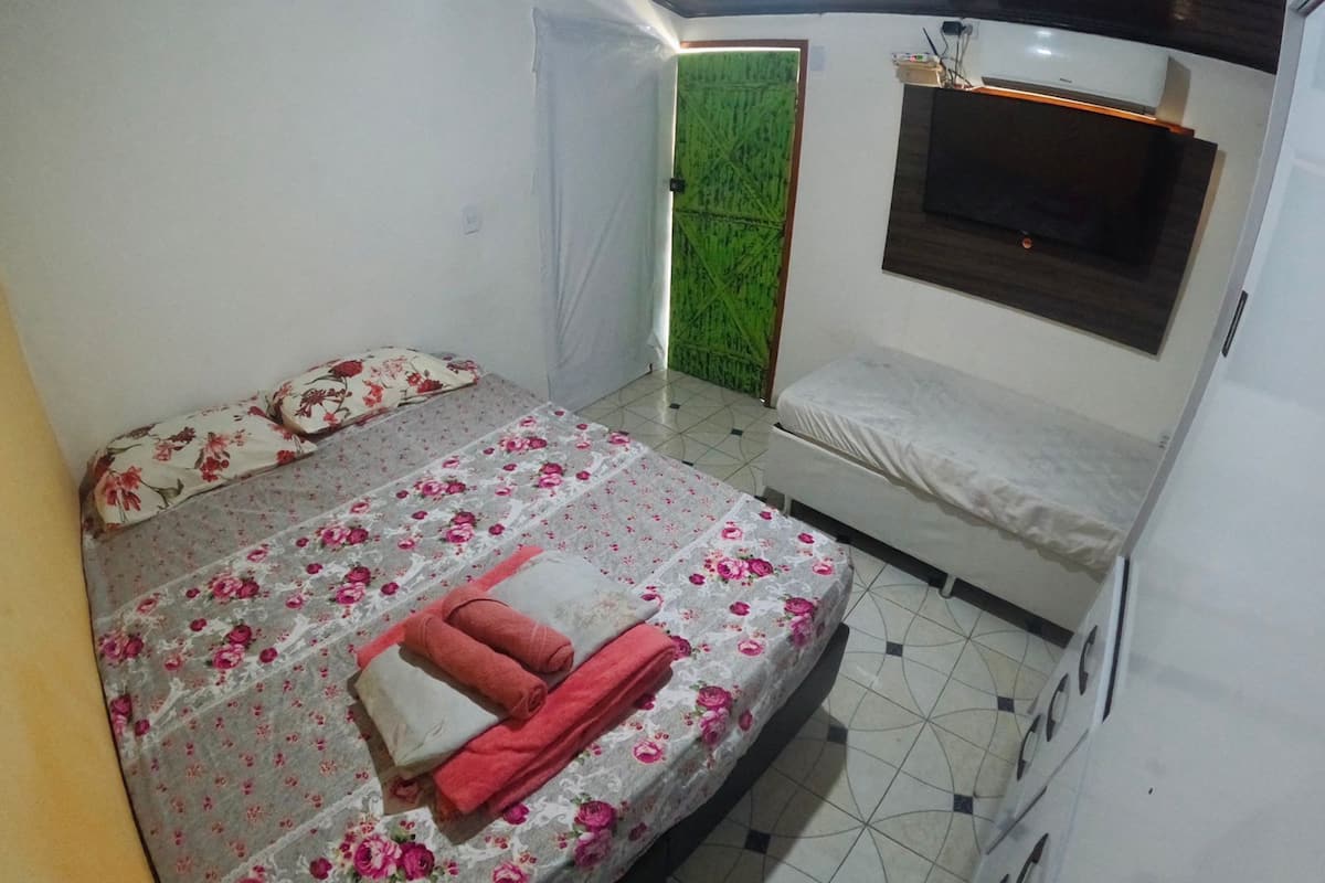 Ein Schlafzimmer mit einem Bett, einer Bank, einem Fernseher und einer grünen Tür.