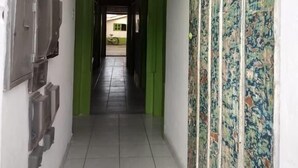 Un couloir doté d’un sol carrelé, de portes vertes et d’un mur orné de motifs.