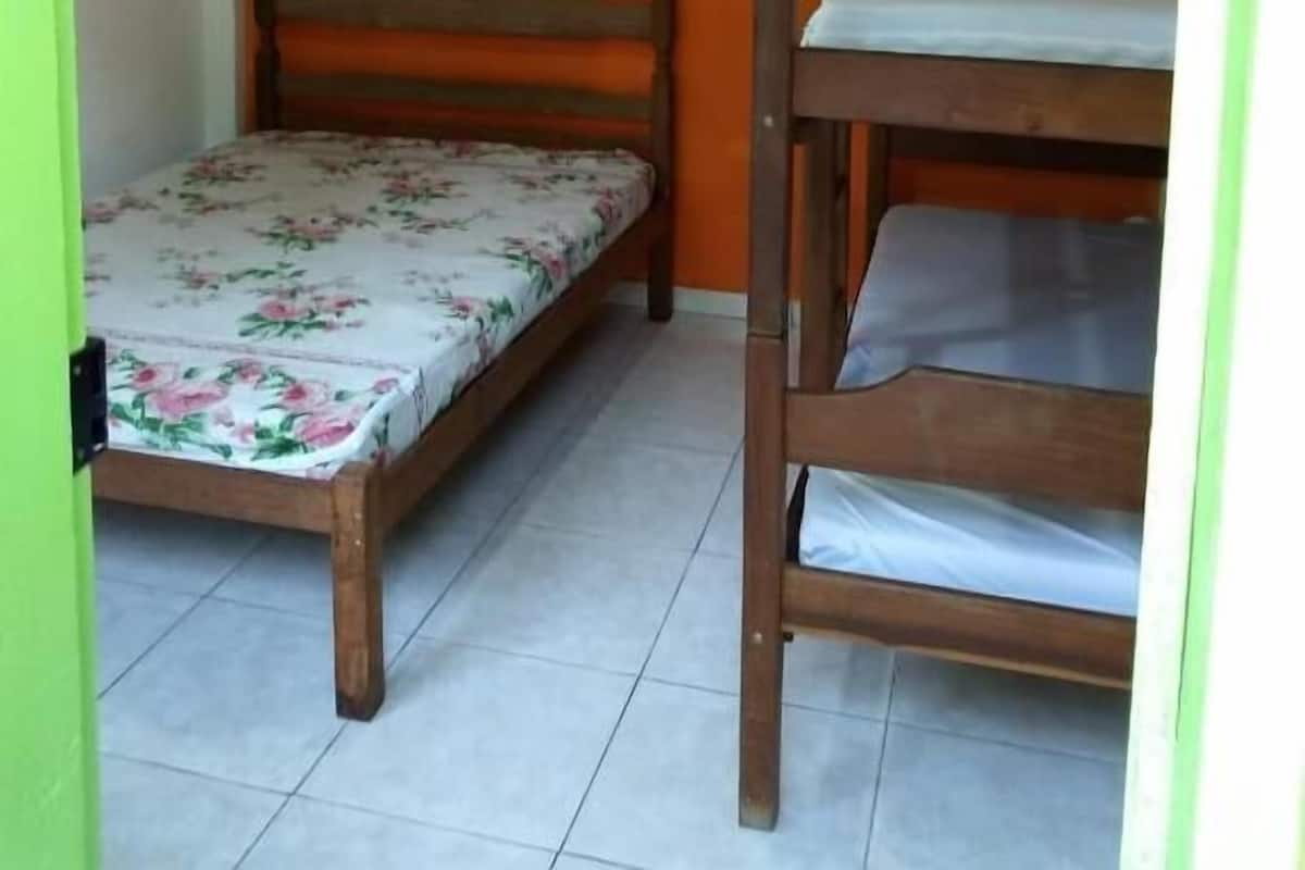 Ein Zimmer mit einem Einzelbett, einem Schlafstockbett und einem Deckenventilator.
