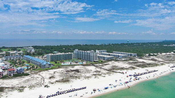 Un resort con varias edificaciones, una playa y un muelle.
