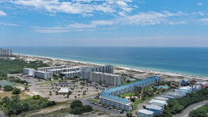 Un resort con varias construcciones, una playa y cielo despejado.