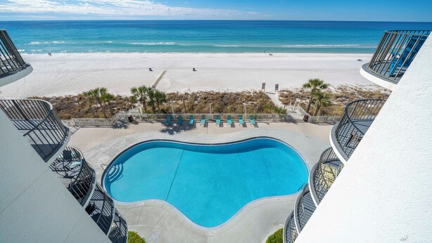 A view of a swimming pool with a beach in the background. - Luxury Beach Front Condo (Panama City Beach)
