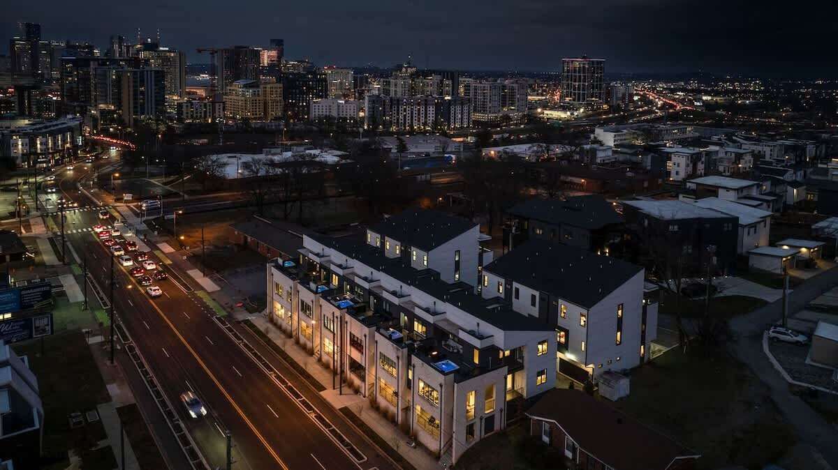 A cityscape at night with a modern building featuring multiple floors and balconies.