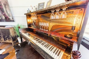 Ett piano med en klassisk, tidstypisk design, omgivet av glasföremål och böcker.