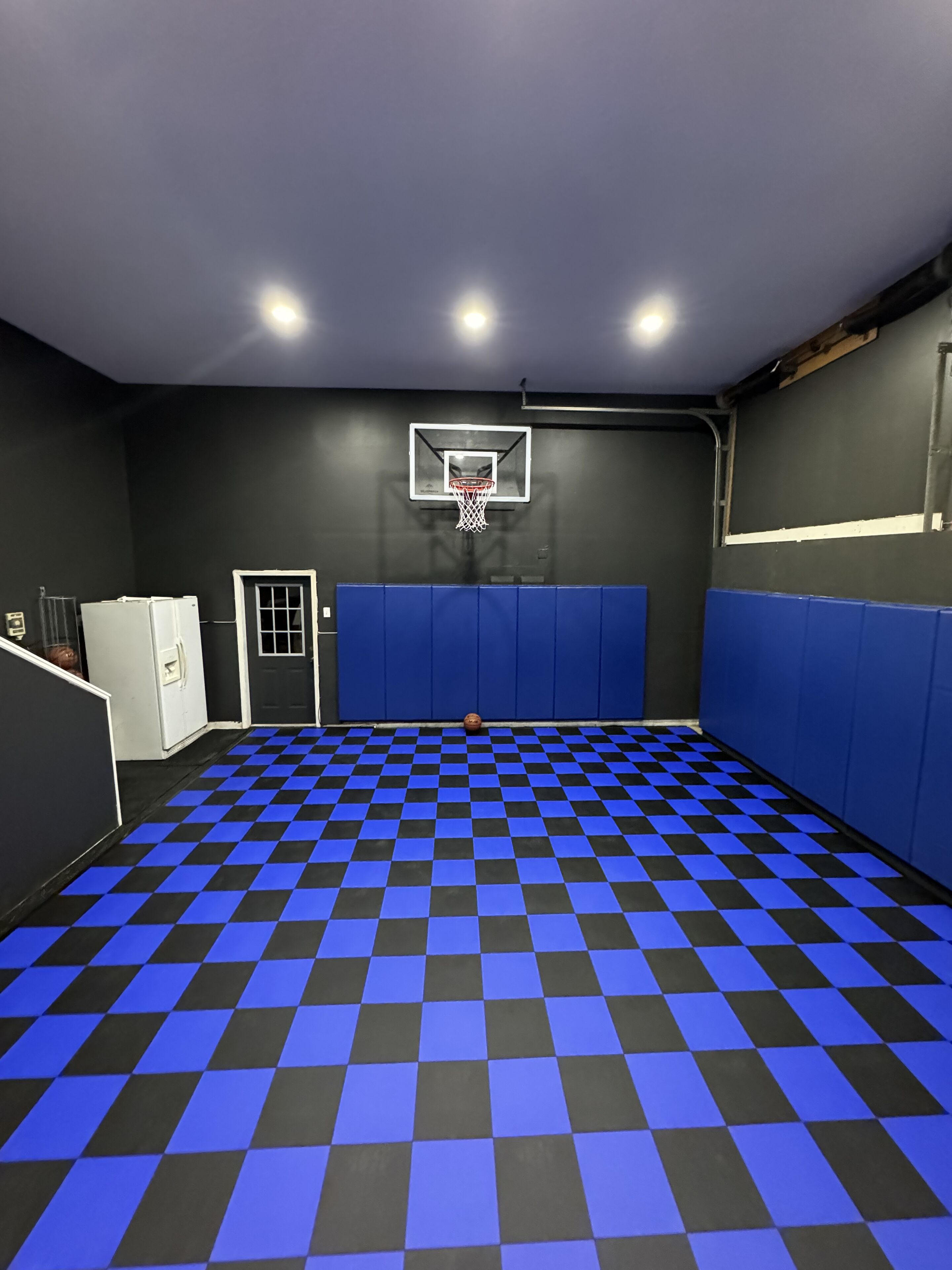 Un campo da basket con pavimento a scacchi, canestro e pareti imbottite.