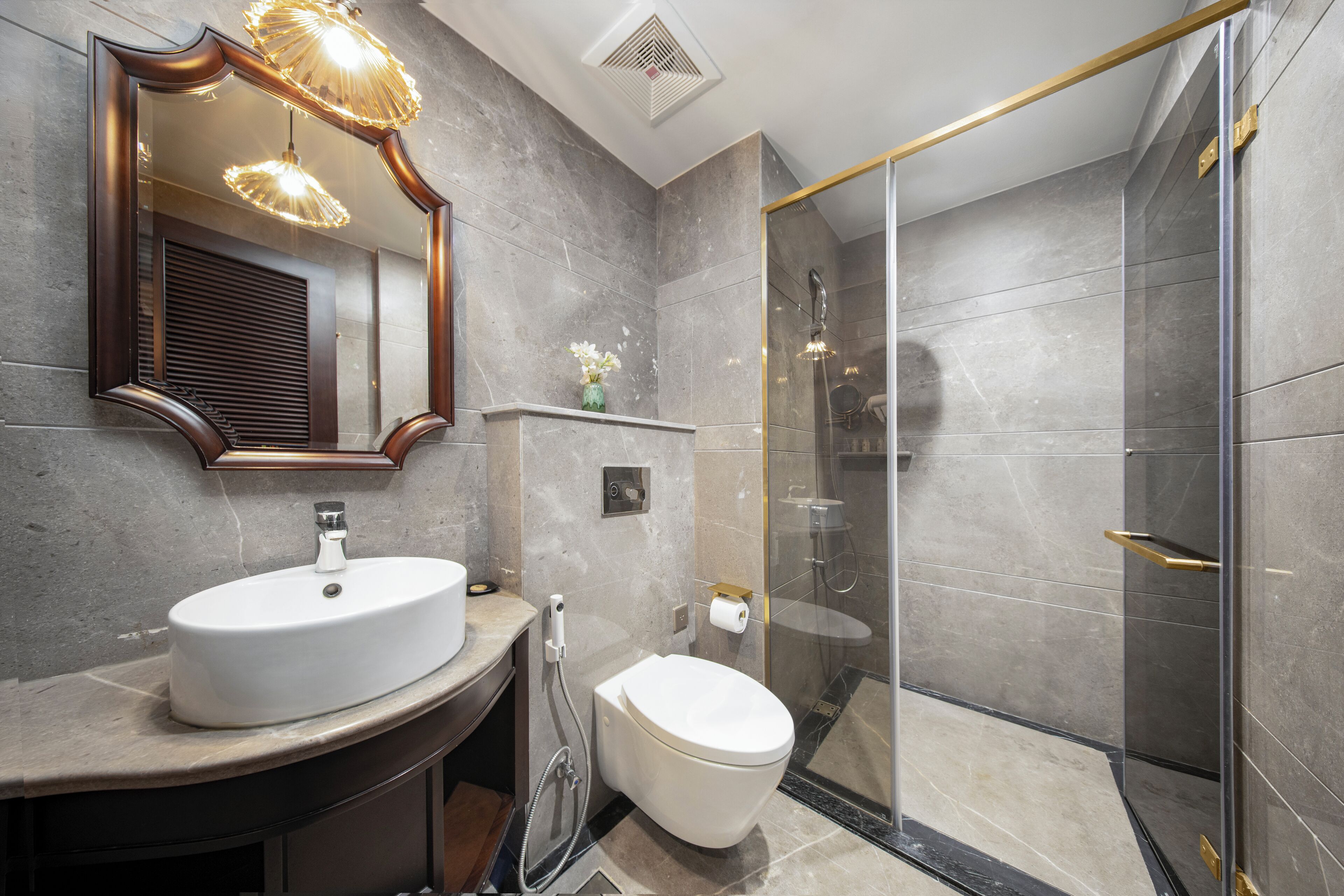 A modern bathroom with a large mirror, a sink, a toilet, and a glass-enclosed shower.