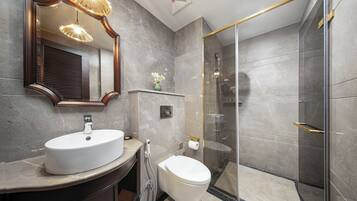 A modern bathroom with a large mirror, a sink, a toilet, and a glass-enclosed shower.