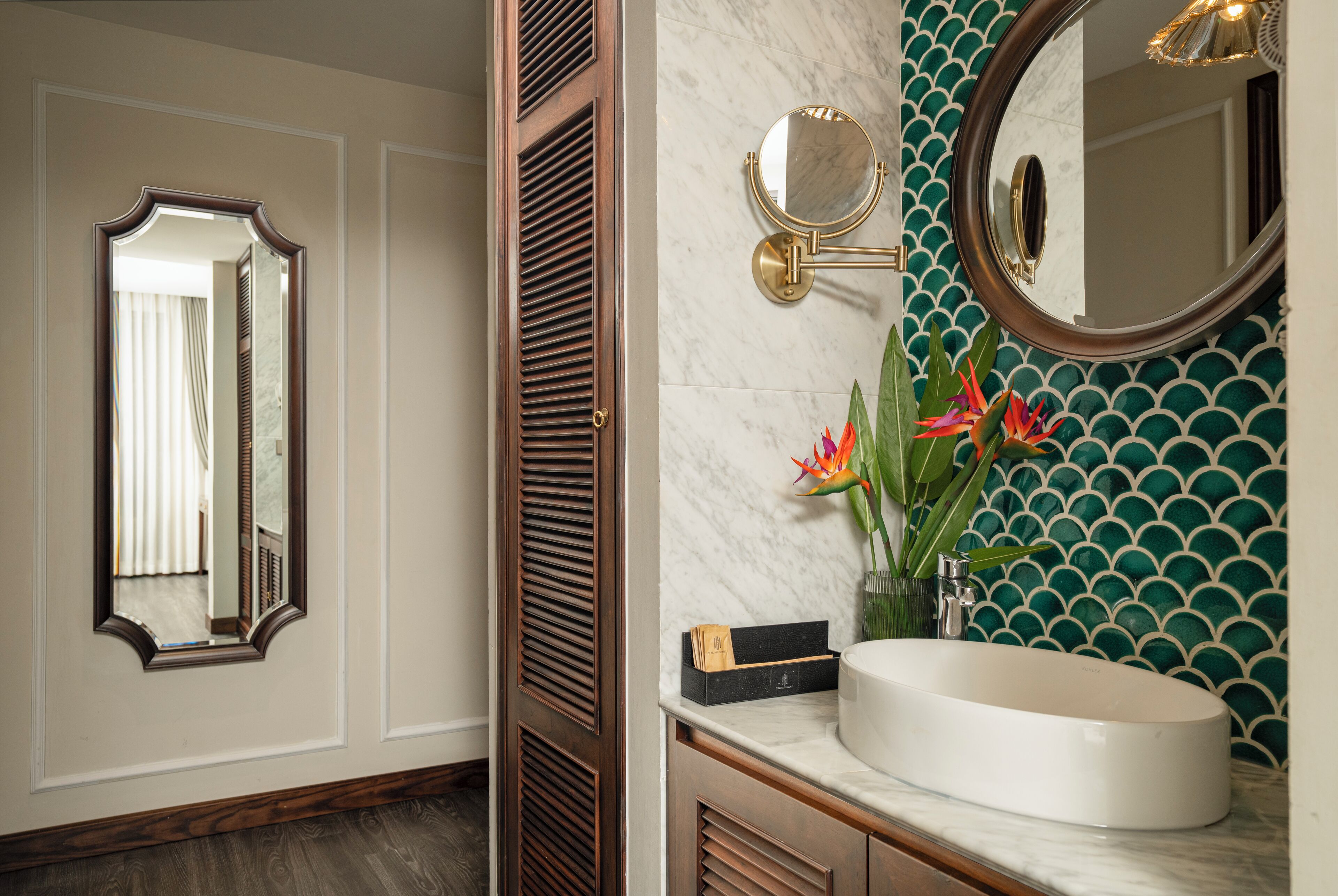 A bathroom with a vanity, a round mirror, and a decorative wall with a green pattern.
