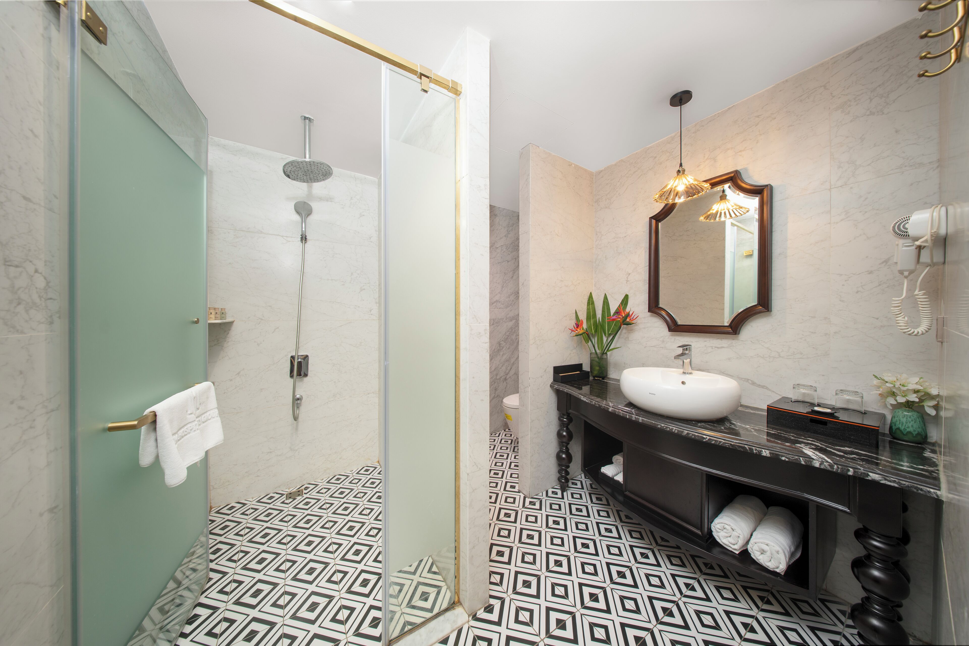 A modern bathroom with a glass-enclosed shower, a marble sink, and a large mirror.