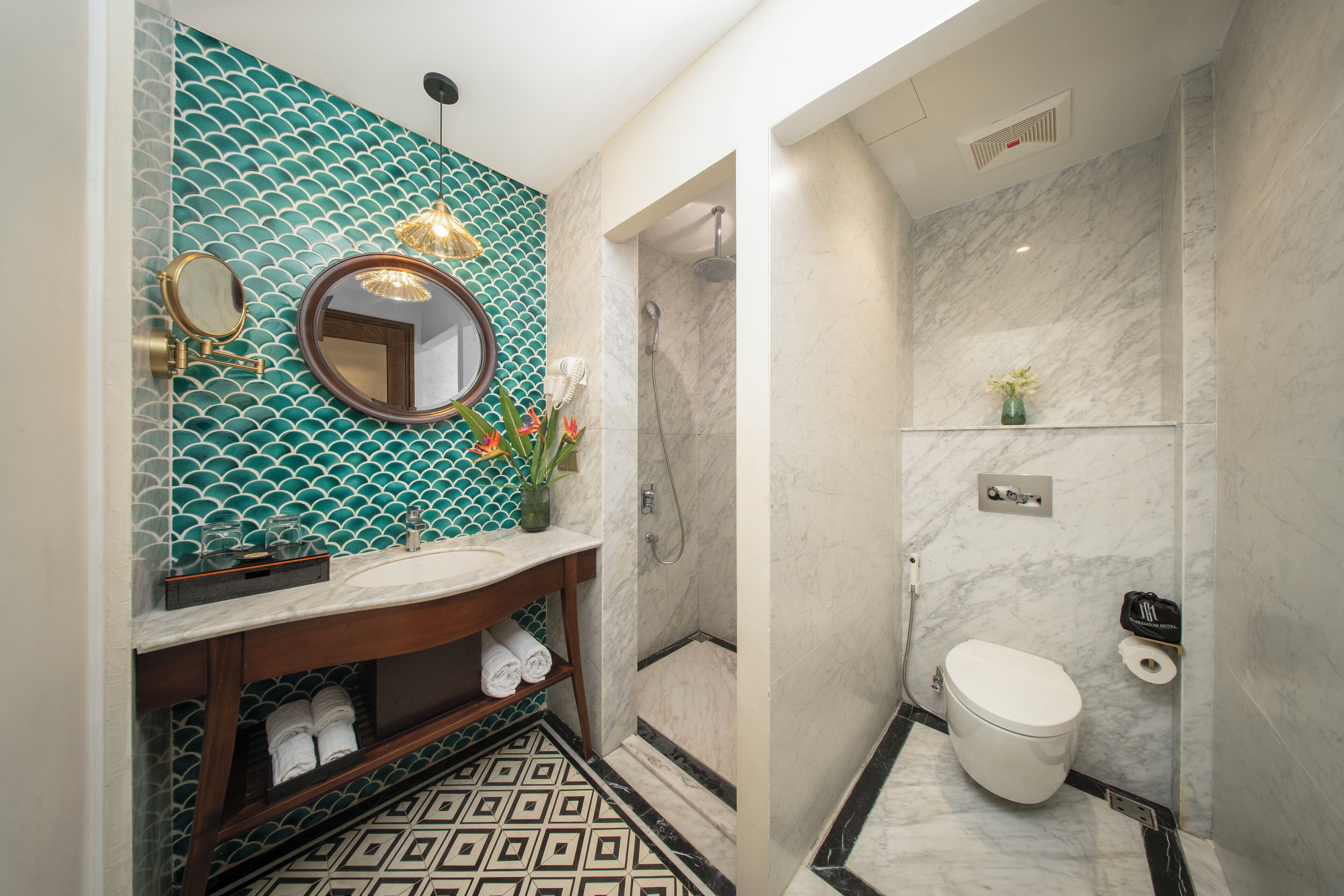 Un baño con pared de azulejos, lavamanos, espejo, inodoro y zona de ducha.