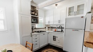 A compact kitchen with white cabinetry, a built-in microwave, a stove, and a refrigerator. - Cozy Lakeside Cabin with Hot Tub (Fawnskin)
