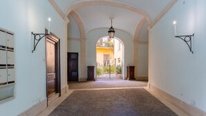 A corridor with arched ceilings, a cobblestone floor, and a gate leading to an outdoor area with plants. - Apartment (Roma)