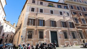 A multi-story building with a classic architectural style, featuring a ground floor with a large entrance door and several windows with shutters. - Apartment (Roma)