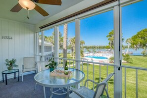 A room with a glass table, chairs, a ceiling fan, and a view of a pool and greenery. - Riverfront Views! Fishing and Boating on the St. John's River, Pool, Boat Slip, All New Furnishings! (Welaka)