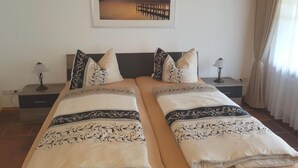 A double bed with matching headboards and footboards, two bedside tables with lamps, a framed picture on the wall, and a window with curtains. - Apartment Steinberg, 2-4 persons, 50 sqm, balcony, TV, 1 bedroom, upper floor (Ramsau bei Berchtesgaden)