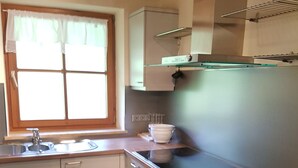 A kitchen with a window, white cabinets, a black countertop, and a dishwasher. - Apartment Steinberg, 2-4 persons, 50 sqm, balcony, TV, 1 bedroom, upper floor (Ramsau bei Berchtesgaden)