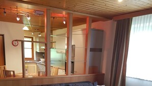 A modern living room with a sectional sofa, a white coffee table, and a kitchen visible through a glass partition. - Apartment Steinberg, 2-4 persons, 50 sqm, balcony, TV, 1 bedroom, upper floor (Ramsau bei Berchtesgaden)