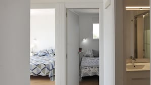 Un dormitorio con dos camas, una ventana y un baño con lavabo y espejo.