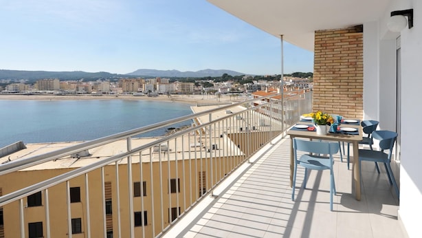 Un balcón con vista al mar y al paisaje urbano.