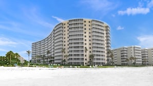 Un hôtel à plusieurs étages, doté d’une façade incurvée, situé juste à côté d’une plage de sable.