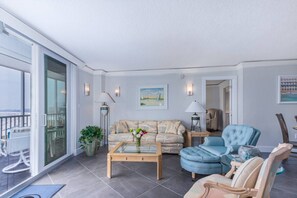A spacious living room with a sofa, armchairs, a coffee table, and a balcony with a view. - 8th-Floor Luxury, Panoramic Gulf Views on Siesta (Sarasota)