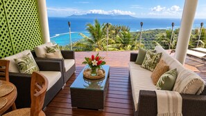 A balcony with wicker furniture, a glass coffee table, and a view of the ocean. - Villa Paradise Tahiti, an extraordinary view with a pool and jacuzzi & free car (Puna'auia)