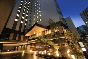 Un hôtel moderne à plusieurs étages, doté d’un éclairage extérieur et d’un escalier reliant les différents niveaux.