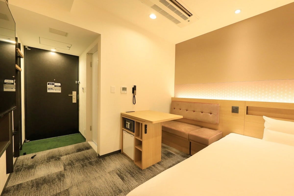 Une chambre d’hôtel comprenant un lit, un bureau, une chaise et un petit coin salon.