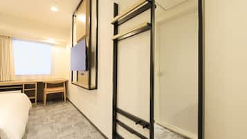 A hotel room with a bed, a desk, a TV, and a wardrobe.
