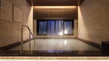 Uma área de piscina coberta moderna, com teto de madeira, paredes azulejadas e uma janela de vidro.