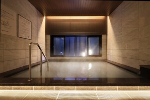Un área de piscina interior moderna con techo de madera, paredes de azulejos y una ventana de cristal.