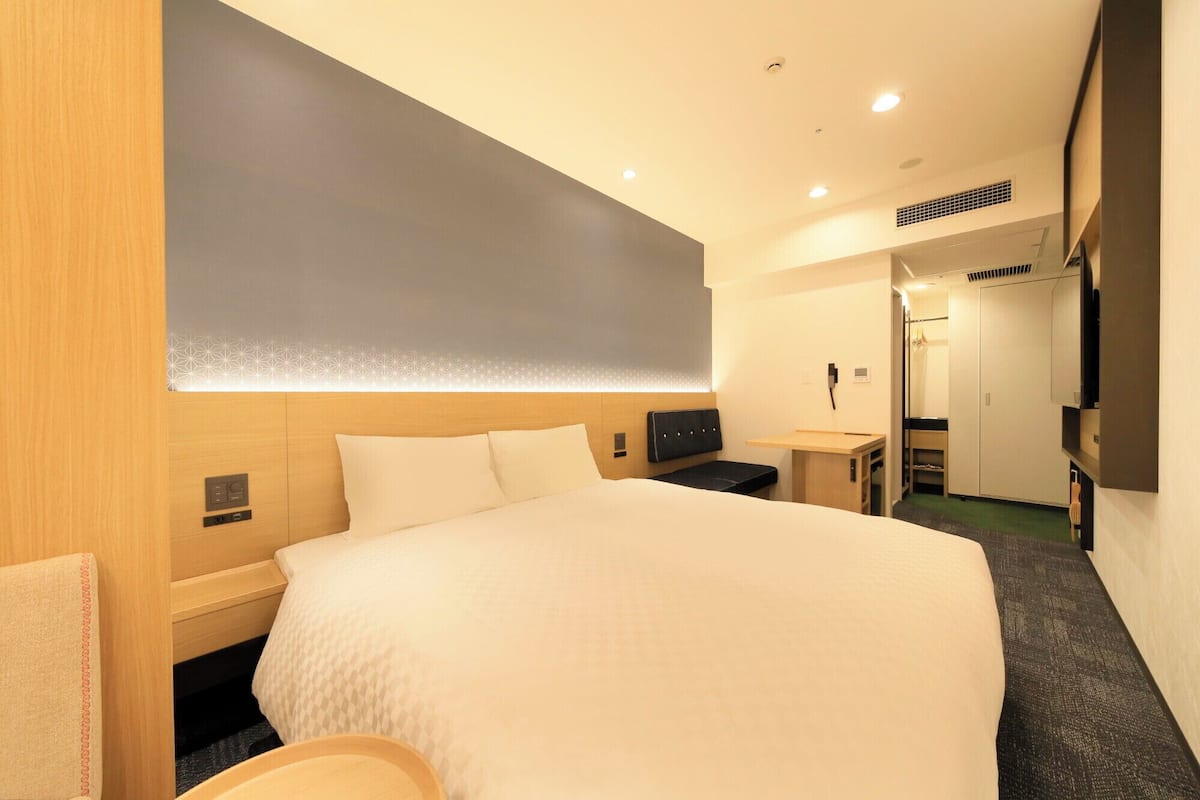 Une chambre d’hôtel avec un grand lit, des tables de chevet, un bureau et une armoire.