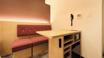 A small, compact room with a wooden bench and a desk with a telephone.