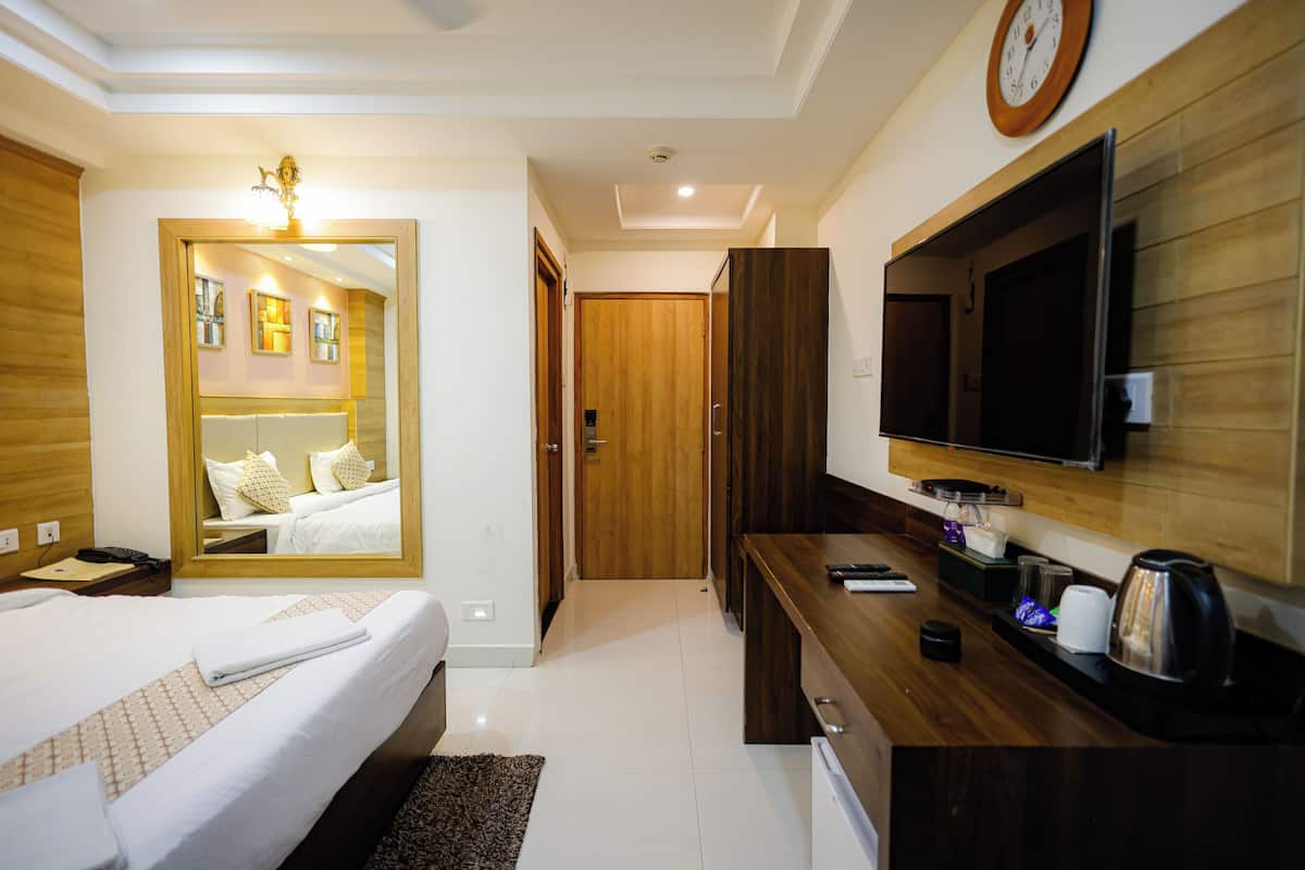 A hotel room with a bed, a desk, a television, and a mirror.
